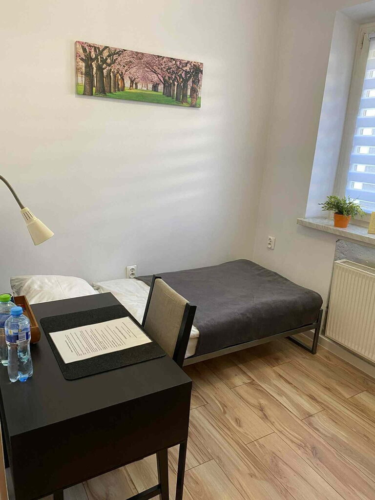 Small, bright room with a single bed, desk, and painting of blooming trees. Small, bright room with a single bed, desk, and painting of blooming trees.